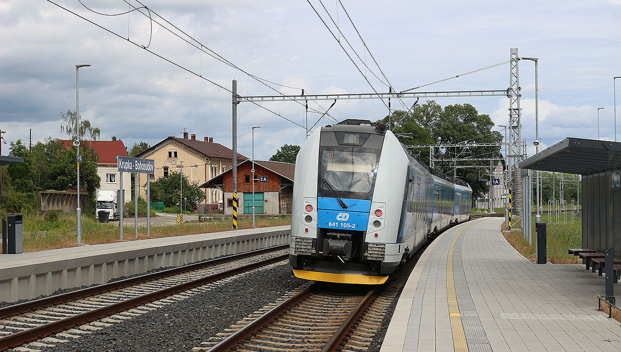 Osobní vlak 6819 na lince U1 DÚK opouští zastávku Krupka-Bohosudov aby vzápětí projel stanicí Bohosudov, která od roku 2023 slouží pouze nákladní dopravě.