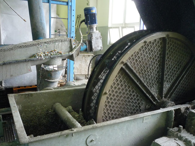 Lahve rozdrcené na několikamilimetrové kousky putují do vodního bubnu, který oddělí částice lehčí než je voda - PET má totiž hustotu 1,37 g/cm3 a klesá ke dnu. Jde třeba o rozemletá barevná víčka z lahví.