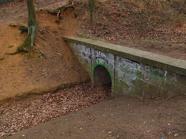 To, co zahrazuje údolí, není přirozený svah ale mohutný, desítky metrů vysoký násep nedokončené dálnice, která tudy měla procházet vysoko nad krajinou. Uzavřené údolí ale bylo třeba odvodnit…
