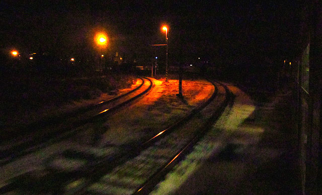 Koleje na odstavné nádraží, nyní přikryté tmou. V dálce svítí Petrov. Za řekou jsme na dolním.