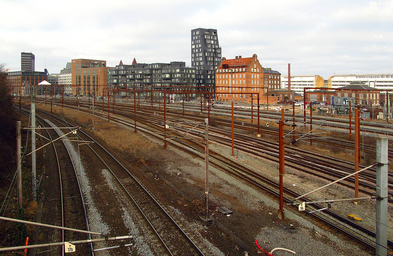 Mě to táhlo samozřejmě spíš k železnici. Nádraží Østerport patří ke větším ve městě a je poslední povrchovou stanicí na trati ze severu (mj. z Helsingøru), pak se železnice noří pod zem. Provoz tu kromě dánských a švédských elektrických a motorových vlaků zpestřuje i městský metrovlak. Dánsko má jeden z nejmenších podílů elektrifikace železnice v Evropě a fungují zde dokonce dieselové dálkové IC4 jednotky. Hlavní tahy jsou elektrifikovány soustavou 25 kV 50 Hz ~, což je nám jihomoravákům blízké, ale Švédové a Němci kvůli tomu musí používat při tranzitu vícesystémové lokomotivy (oba státy používají systém 20 kV 16 2/3 Hz ~). Po chvíli marného hledání pokladny mezi stánky s občerstvením se mně podařilo v automatu koupit poněkud drahou jízdenku do švédského Malmø (172 DKK = 600 CZK) a chytit jeden z mnoha taktových vlaků, co pod mořem spojují obě země. Zajímavá severská architektura okolo nádraží je skoro samozřejmostí.