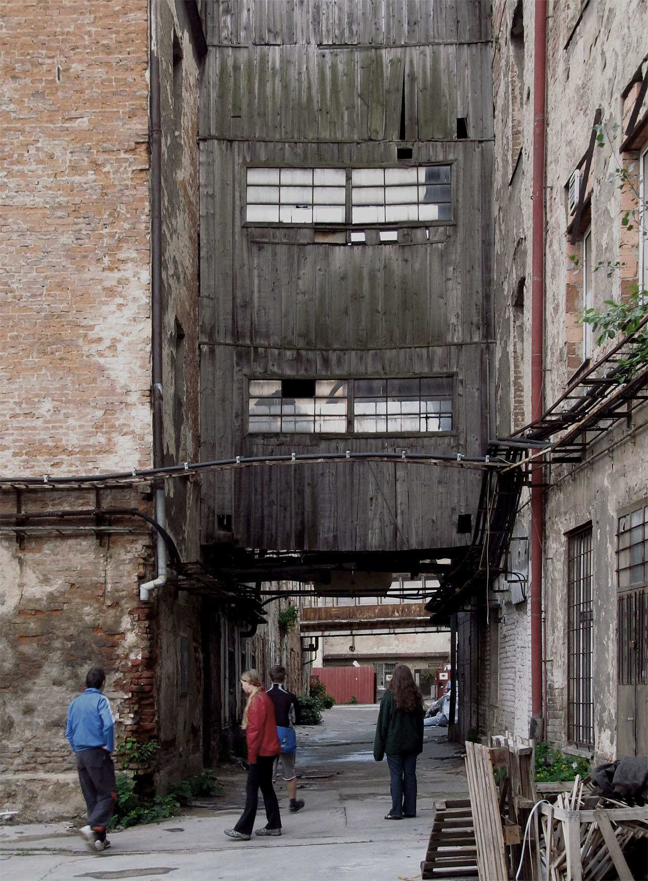Přibližně před sedmi roky jsme tehdy relativně čerstvě opuštěnou Vlněnu navštívili poprvé. Tenkrát bylo ještě možné bezpečně proniknout do dřevěných průchodů mezi budovami, kterými projížděly vozíky s přízemi a textiliemi, všude se povalovaly spousty cívek a kovových součástek, jejichž účel je mně dodnes skryt. Dnes už bychom se na dřevěné rampy asi báli vkročit.