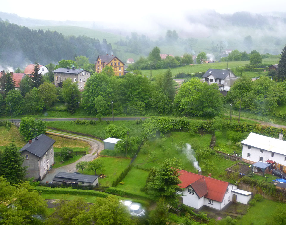 Deštivý pohled z viaduktu na Fabrycznou ulici v Ludwikowicích je symfonií sudetského urbanizmu staveb roztroušených v kopcovaté krajině.