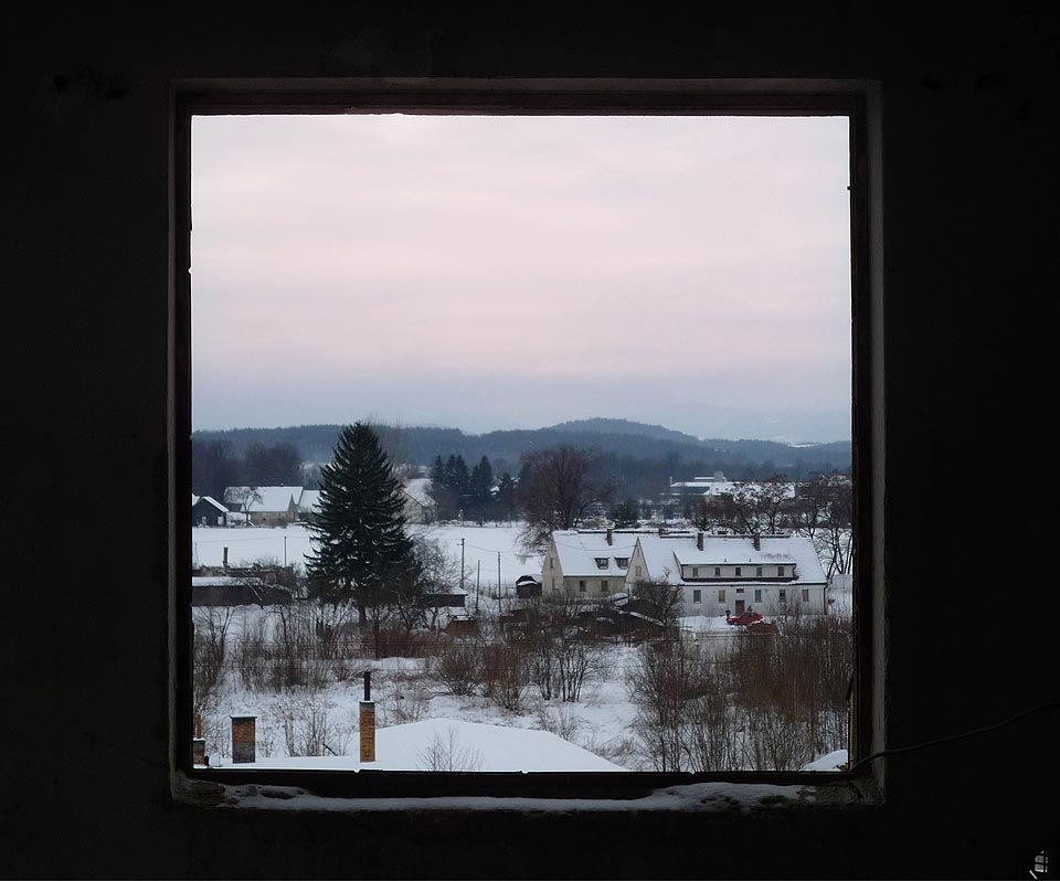 Rozbitými okny továrních hal profukuje vítr a venku nad sudetskou krajinou pomalu vyhasíná den.