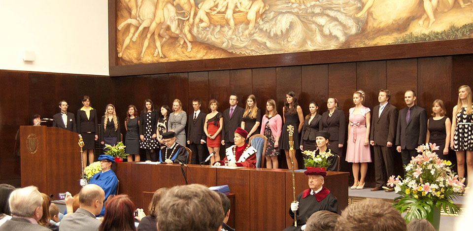 …řadí se pod nahým pozadím lidí, jež se právě učí krotit býky, novopečení magistři a magistry (plus jedna doktorka).