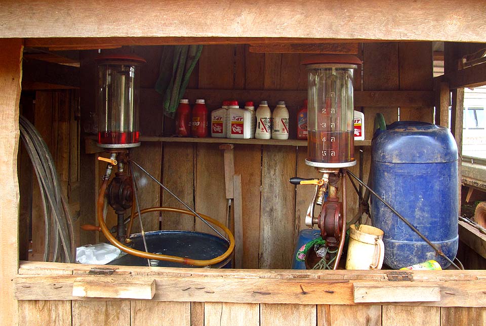 Typická venkovská benzínka v Laosu. Prodavač vám načerpá benzín nebo naftu do skleněného válce a hadicí samospádem přeleje do nádrže.