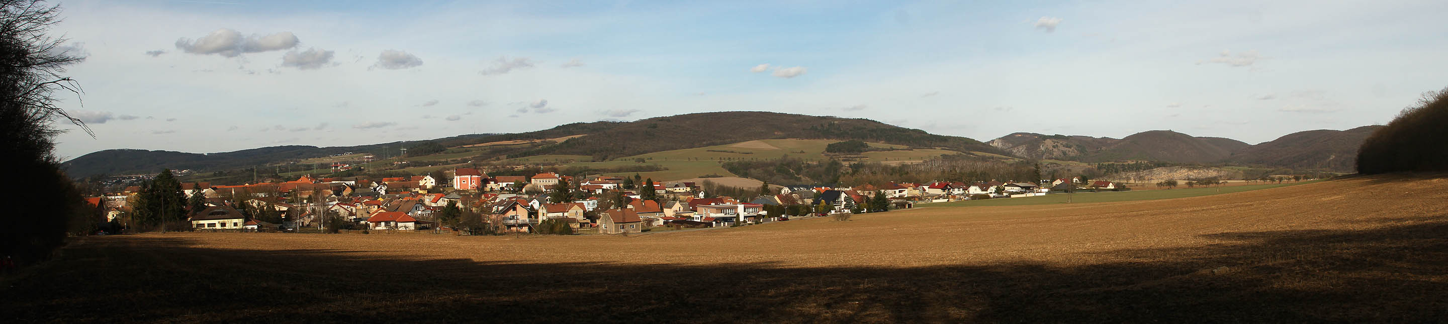 Vesnice <a href=http:/Tema/Tet%C3%ADn%20(ORP%20Beroun)>Tetín</a> při pohledu od jihu - z lesa.