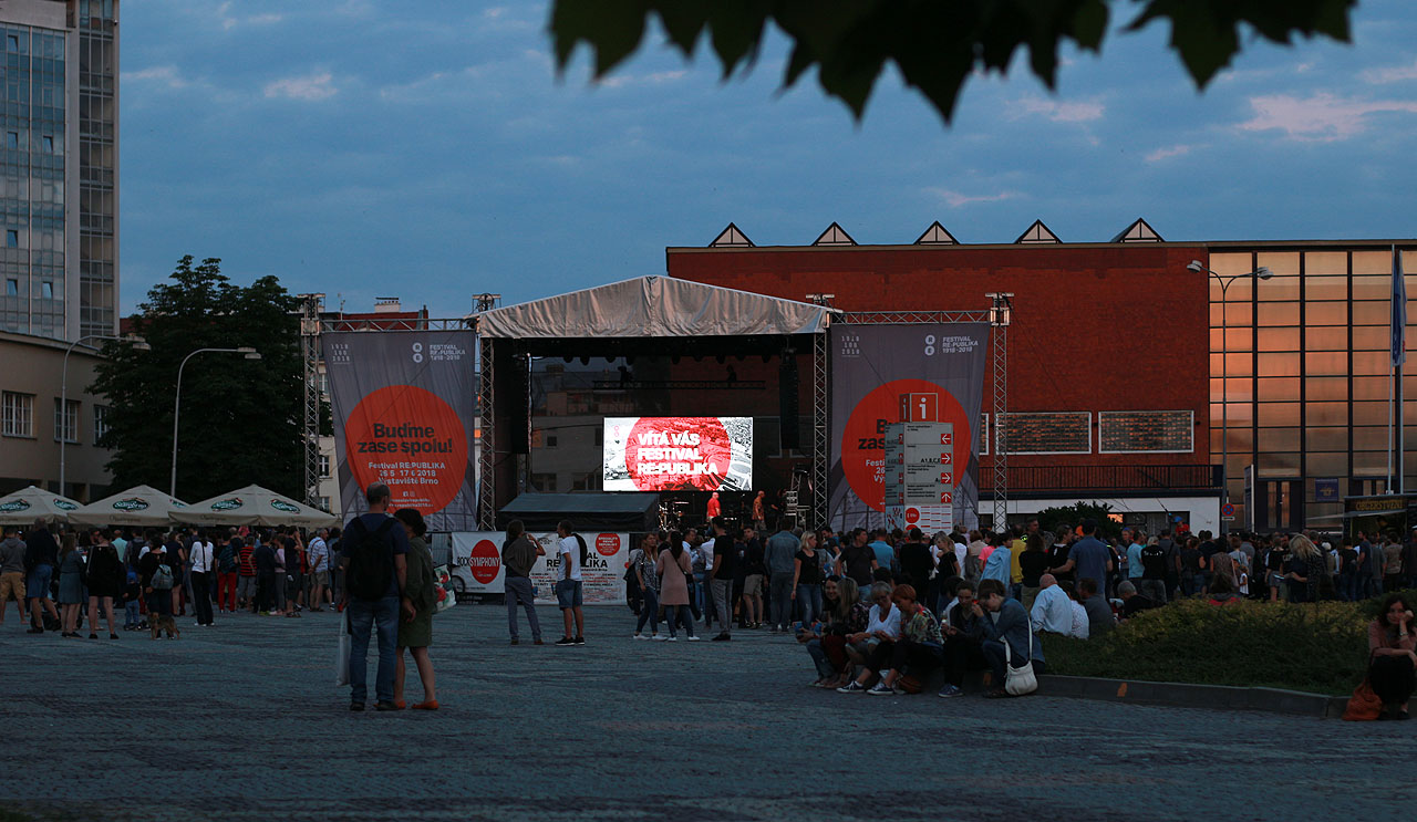 Vítá vás festival RE:PUBLIKA, poloprázdné výstaviště a hloučky postávající u stánků s nápoji.