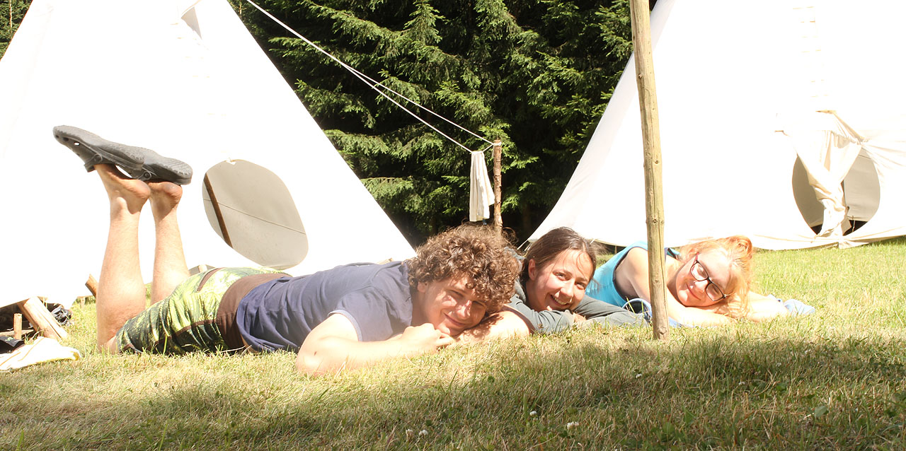 Polovina letošního týmu vedoucích. Ilič, Doubravka a Nancy odpočívají před týpkem v trávě poté, co byla (na stavěčce) všechna práce udělána.