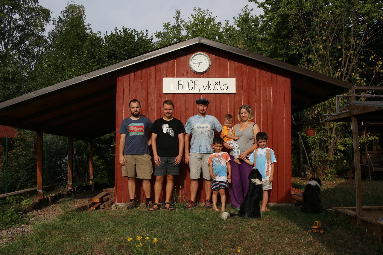 Železniční zastávka Liblice, vlečka je zatím bez koleje, zato výdejna jízdenek je již dokončena. Na unikátní zahradě s kouskem 700 mm úzkokolejky jsme se vyfotili s rodinou Tinky a Winogy (už bez Winogy): zleva Jindrou, Vojtou a Vaškem a psy Doubravkou a Borůvkou. Děkujeme za útulný kout české země k výživnému přespání.