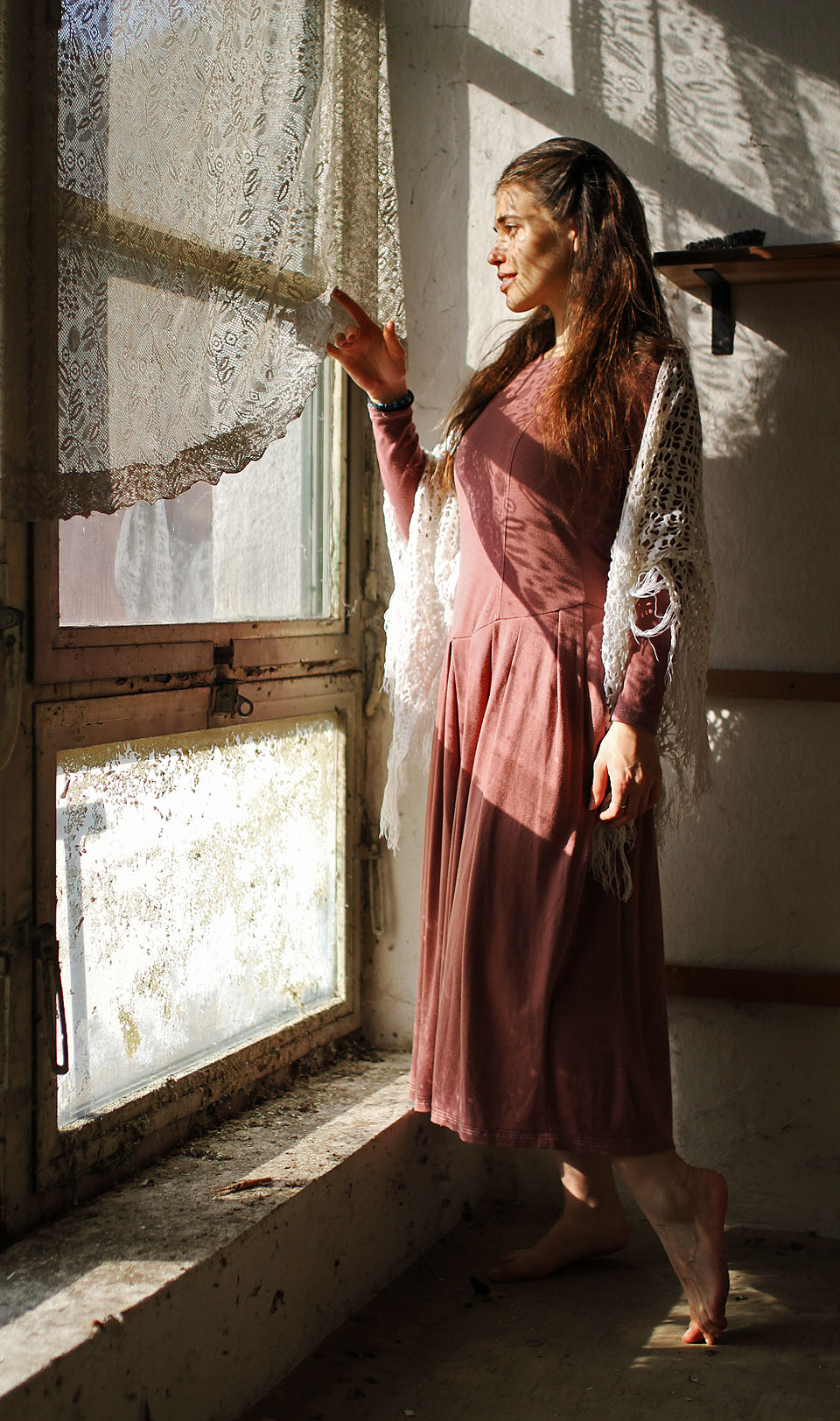 Anička za záclonou v šatech, kterým říká „babičkovské“.