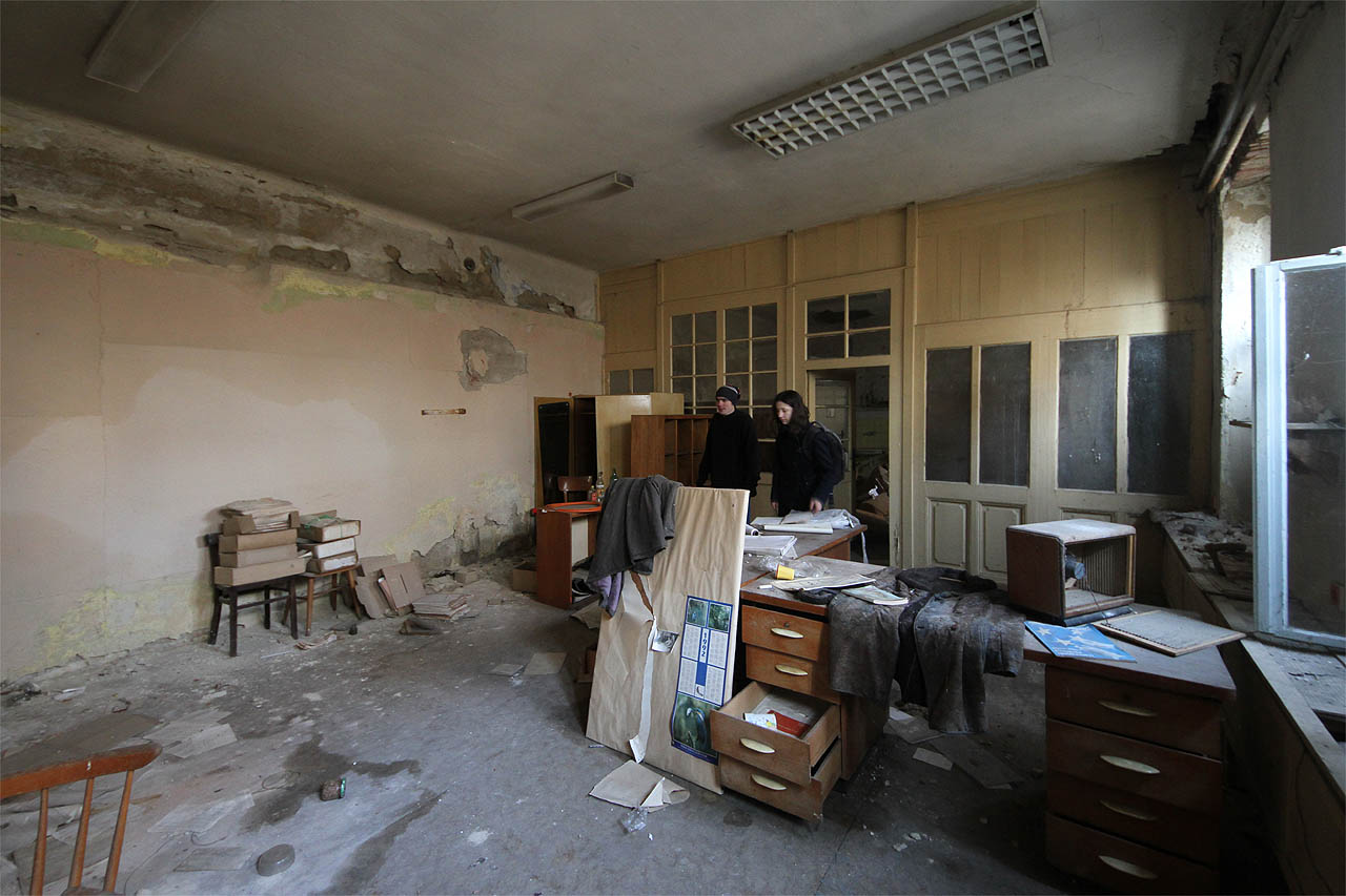 Všudypřítomná vlhkost a plíseň jsou jedinými obyvateli dávno vyrabovaných kanceláří. Přemýšlíme, kolik let tady, za vysokou zdí, nebyli lidé.