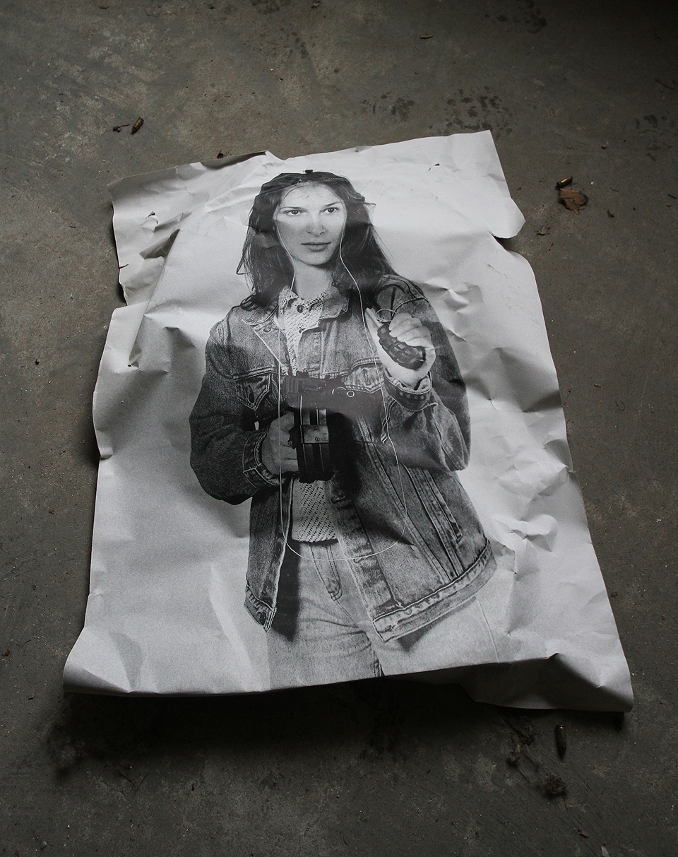 …že jediná přítomná dívka na nás hledí z plakátu a v jedné ruce drží škorpion a v druhé granát.