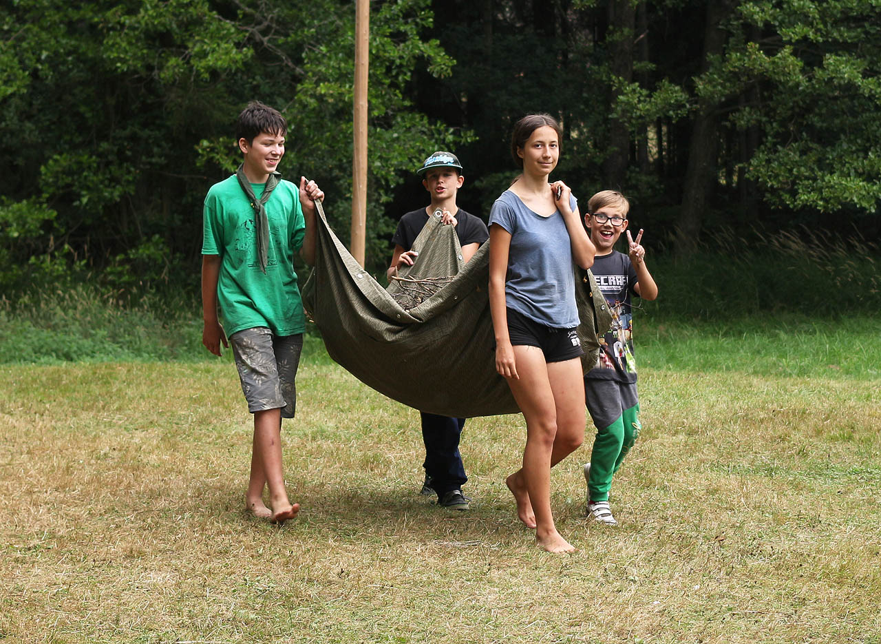Vodník, Péťa, Doubravka a Adam nesou chrastí na závěrečný oheň.