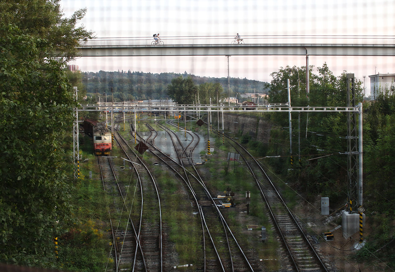 Pod starým nadchodem blednoucím před výší nové lávky se krčí pár zadních kolejí představujících hřbitov lokomotiv.