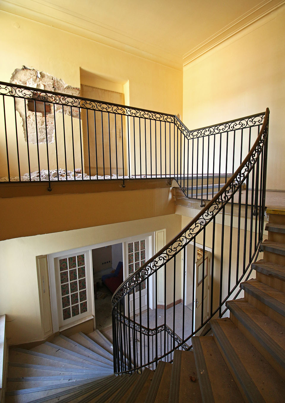 Velkolepost hlavního vilového schodiště stroze sráží gumové lišty linolea na jeho stupních.