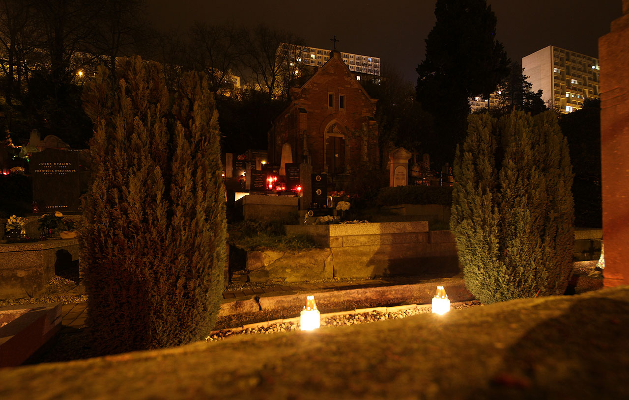 Původní márnice starého hřbitova na kraji obce se dnes krčí pod příkrými stěnami paneláků šplhajících do temného nebe.