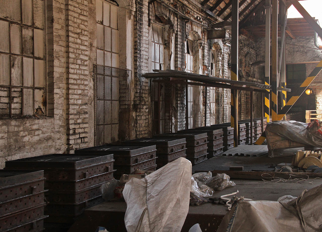 Úzkokolejné vozíky s prázdnými licími formami čekají na odstavné koleji na dvoře před slévárnou.