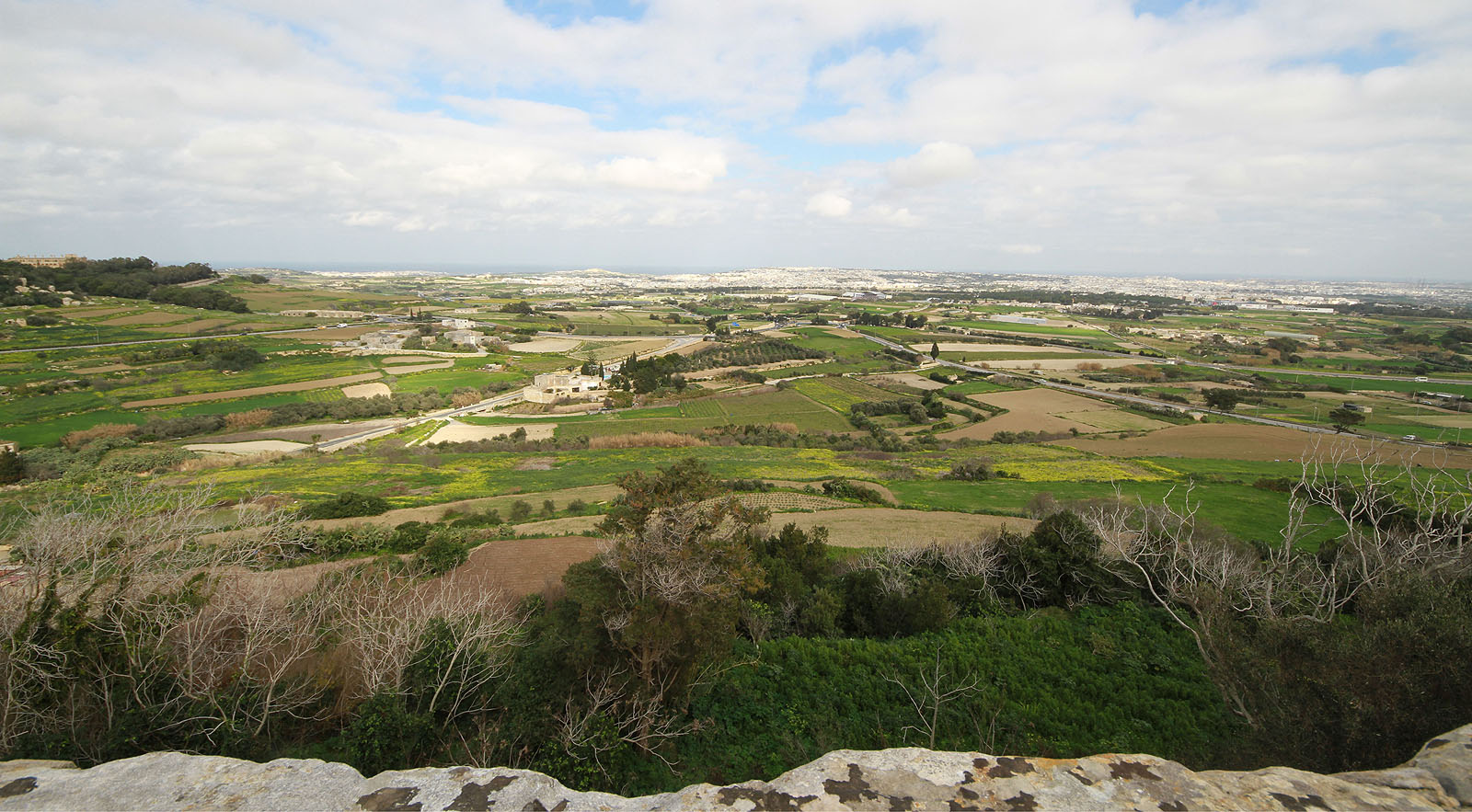 Výhled z mdinských hradeb směrem na hlavní souměstí  Valletta, Marsamxett, Floriana, Birkirkara, Qormi, Żabbar, Bormla, Birgu, Isla, Kalkara, Fgura, Raħal Ġdid, Ħamrun, Marsa, Furjana, Imsida, Ta