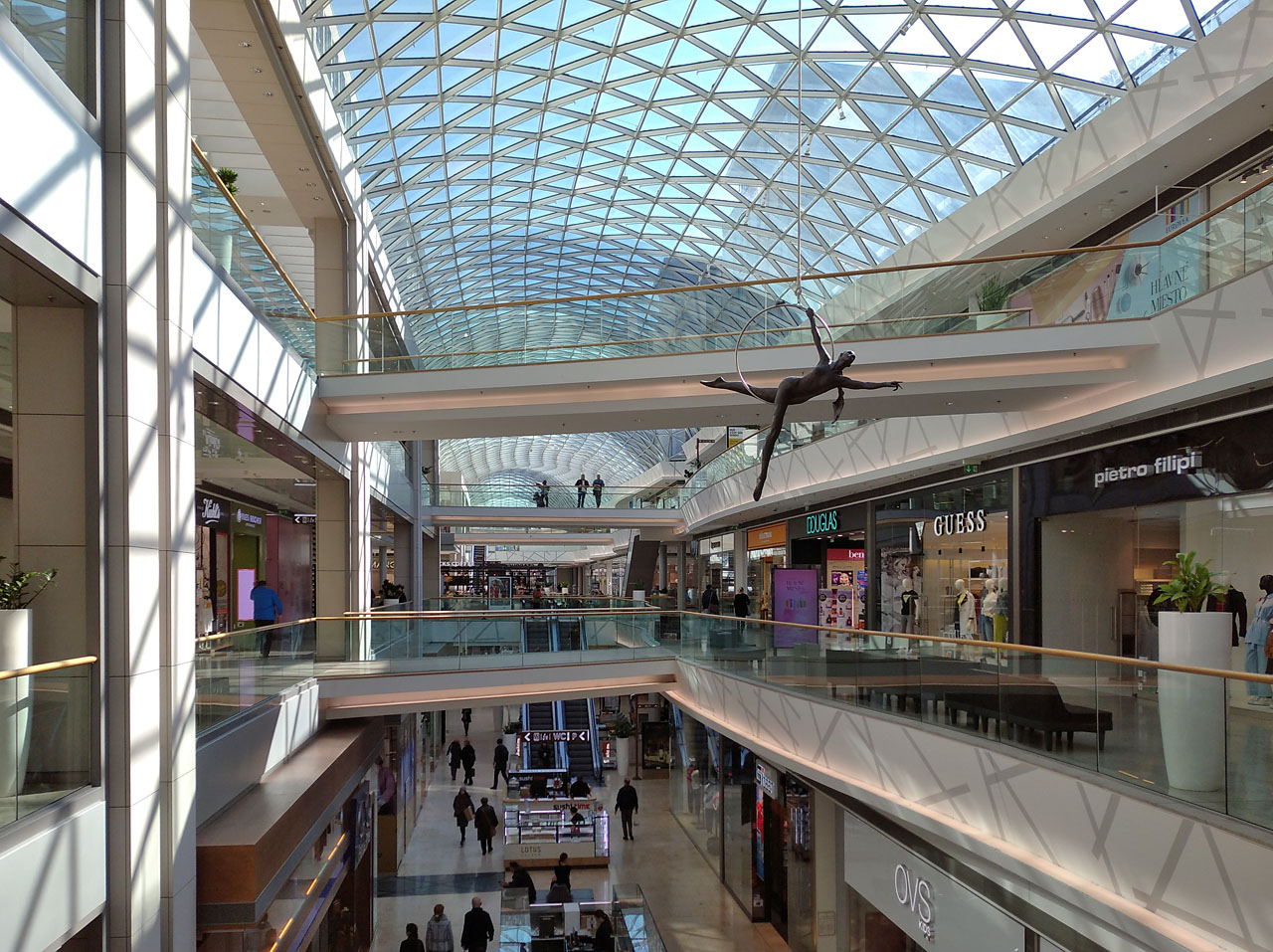 Na kruhu se houpe pro změnu bronzová Yulia. Dost vysoko na to, aby v případě pádu způsobila nepříjemnou chvilku nakupujícím v sále pod ní.