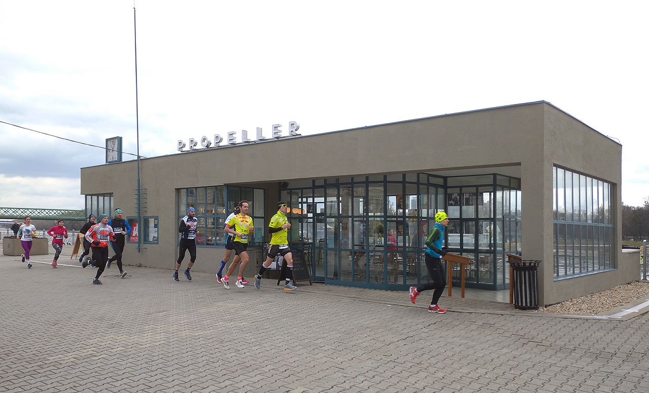 Přístaviště přívozu s prozaickým názvem Propeller a okoloběžící maratónští běžci, kteří to vzali raději po Novém starém mostě.