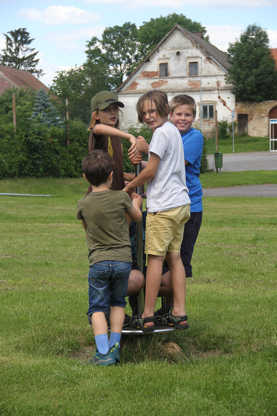 Cestou z Olešenky jsme se tradičně zastavili na dětském hřišti. Postupně se učíme své přezdívky a poznáváme se. Nejmladšímu Adamovi, který právě nastupuje na kolotoč, je teprve 6 let!