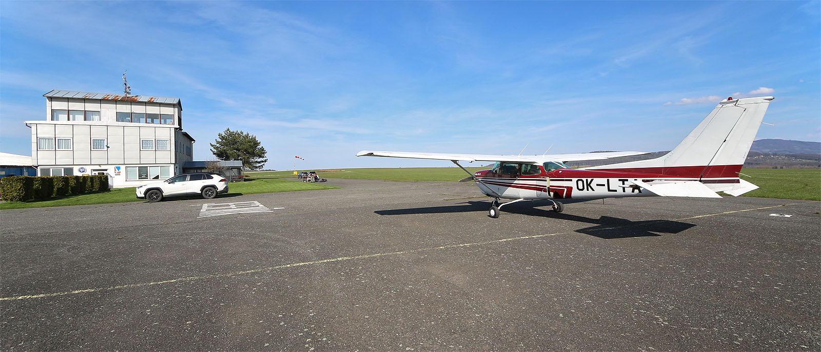 Provoz není velký. Před hangárem stojí vystavený dvojplošník An-2 a pán v trenýrkách seká trávu okolo věže. Jinak se nikde nic nehýbe.