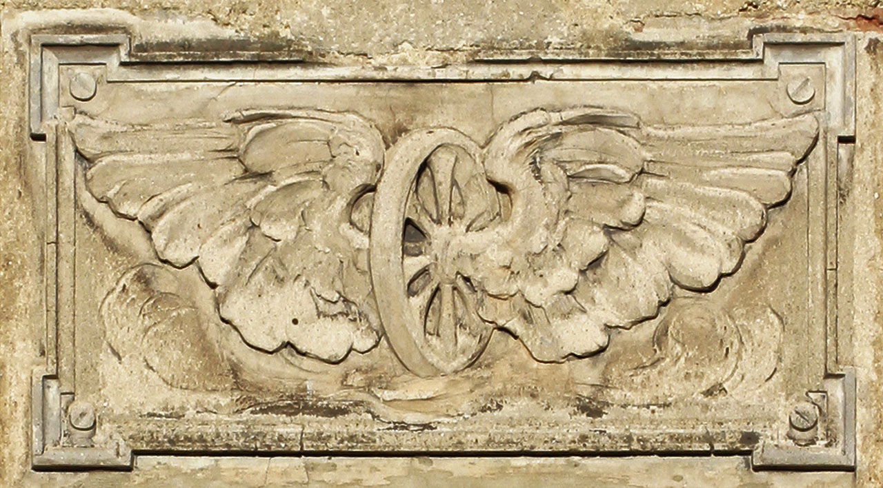 …a málokdo by taky našel reliéf s okřídleným kolem, usvědčující fasádu z historické skutečnosti. Ano, zde se nacházela stanice úzkorozchodné dráhy Slaný–Kačice, nazvaná Šternberk-Smečno.