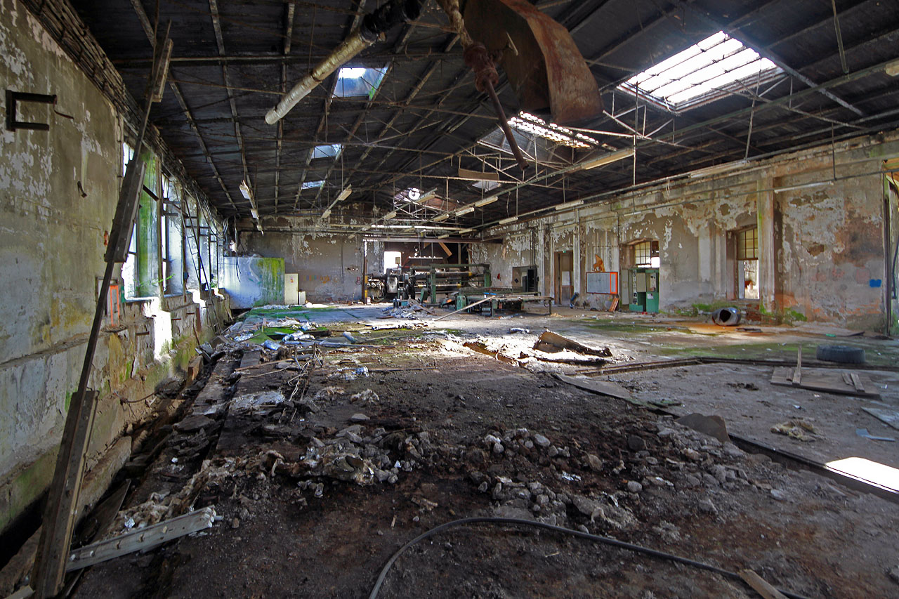 Za vyvrácenou branou nás vítá hluchý prostor a v něm poslední zbytky strojů.