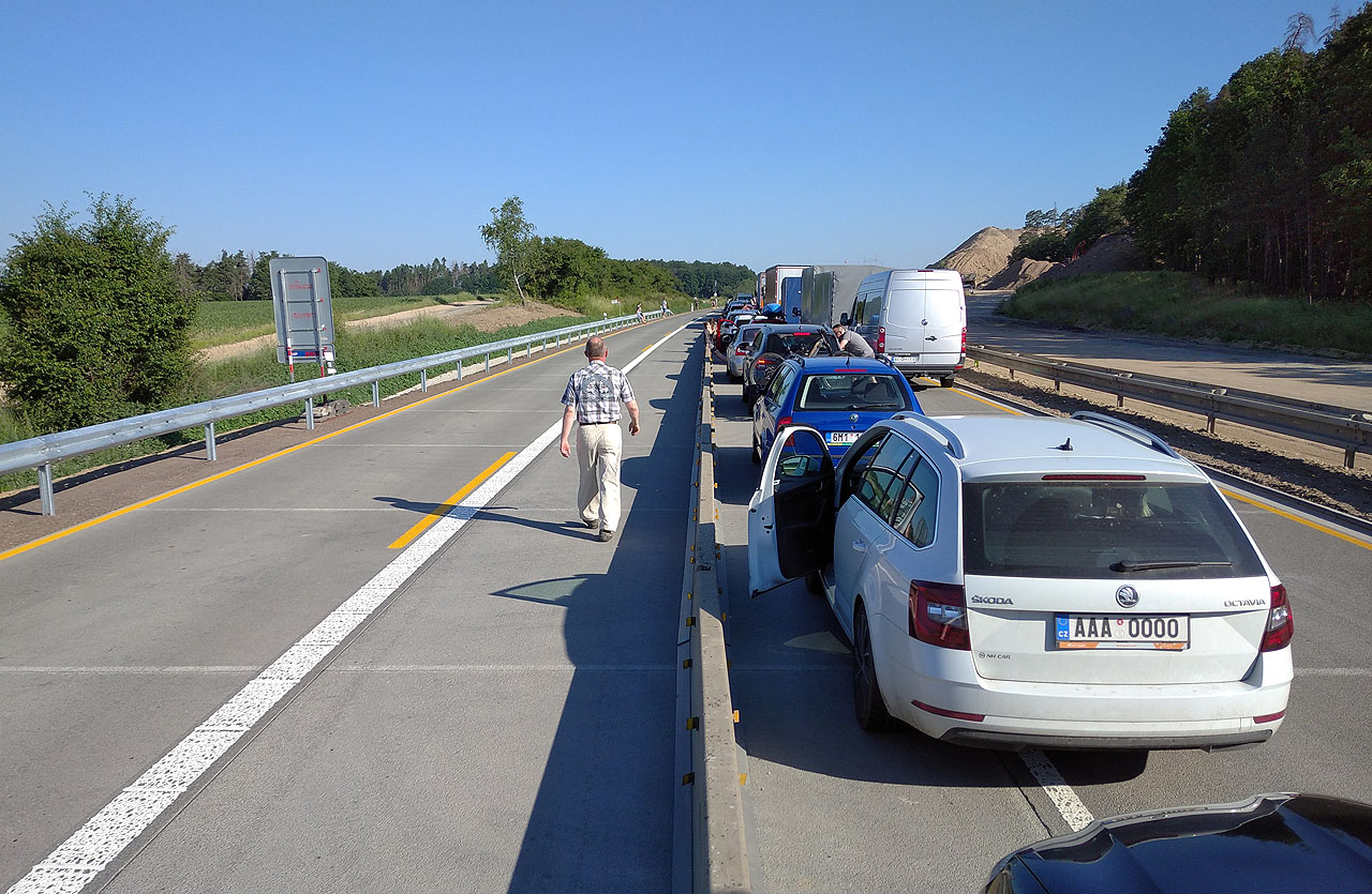 Neudeřila ještě ani osmá hodina ranní a doprava po dálnici nám ukázala svoji odvrácenou tvář. Kdesi v dálce před námi se převrátil kamion a začal hořet, načež doprava ve směru Praha – Brno úplně zkolabovala a náš směr se zastavil. Vojtův kamarád ze Silůvek se zcela bez servítek vydal po vozovce v protisměru pěšky. Čekali jsme asi půl hodiny a když se kolona rozjela, riskovali jsme život, abychom ho zvládli nabrat mezi svištícími auty.<br>
Příště jedu určitě vlakem.