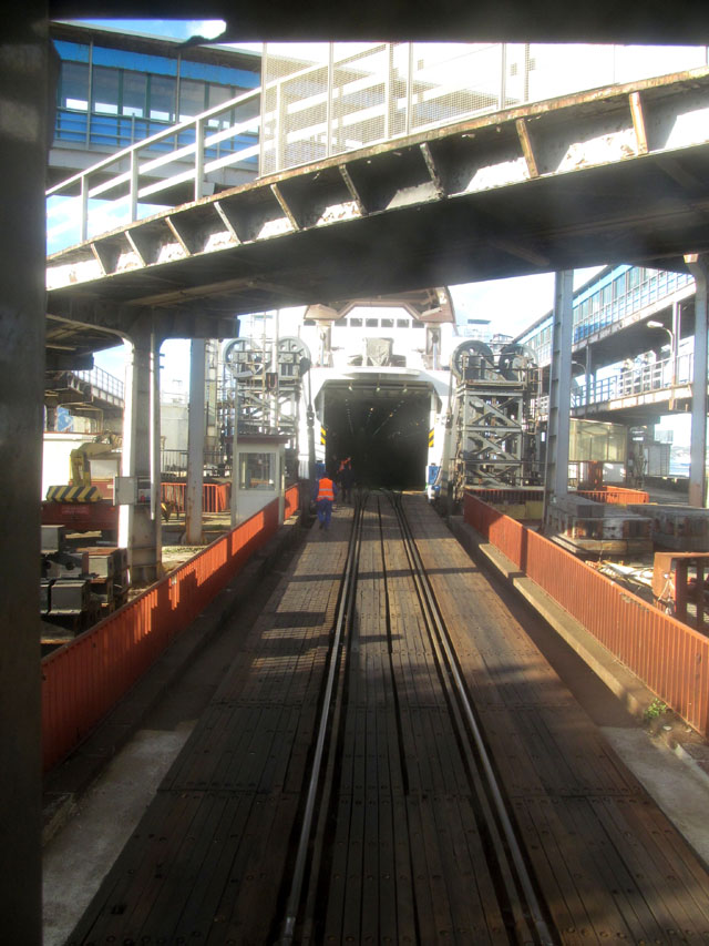 Vlak najíždí na trajekt s cestujícími.