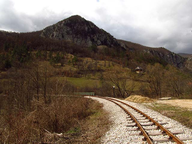Nad tratí se na kopcích pasou ovce, tráva se nesměle zelená a na vše shlíží domky s typicky strmými střechami.