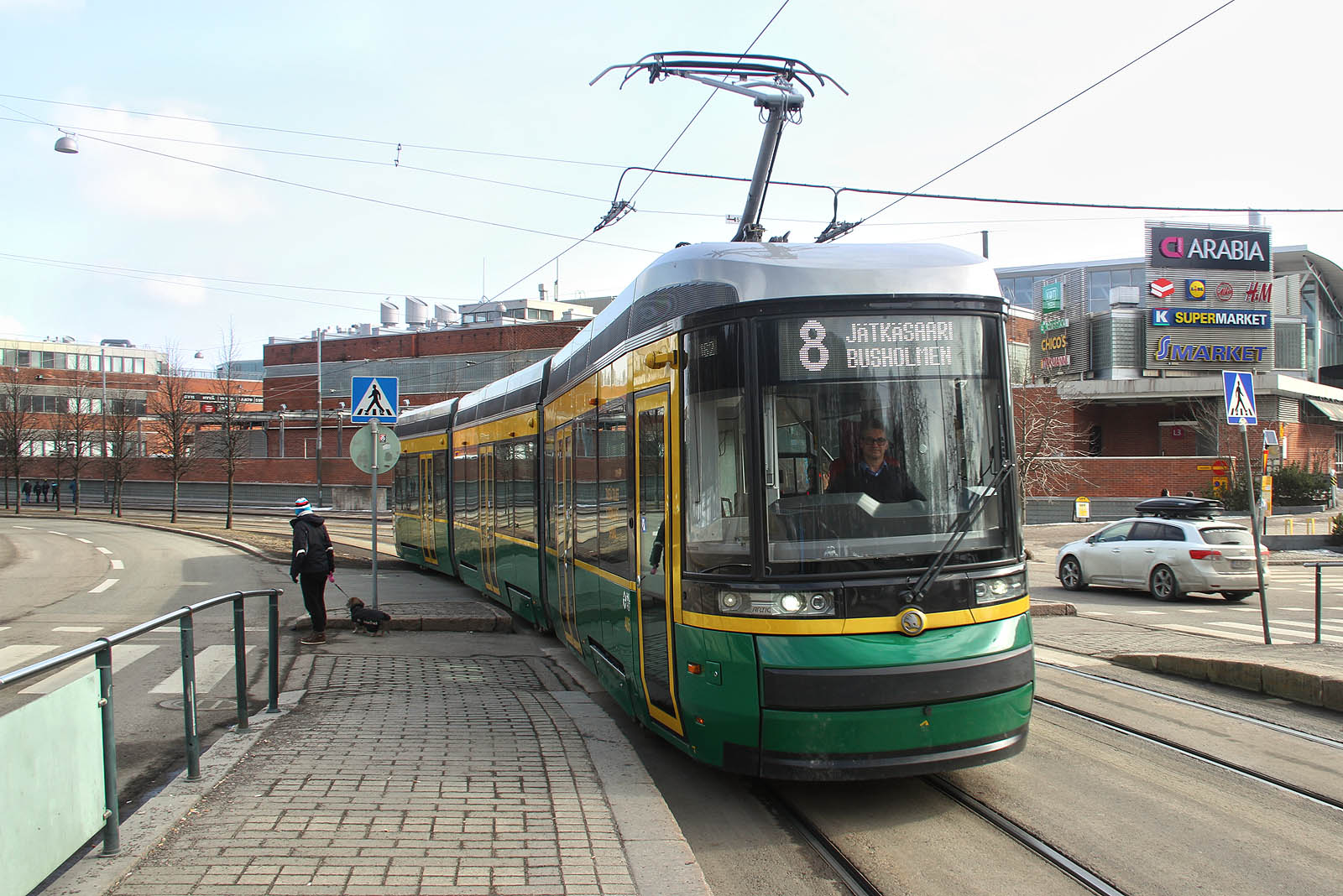 Tramvaj Škoda Artic na lince č. 8 v Helsinkách vjíždí k nástupiši zastávky Kyläsaarenkatu.