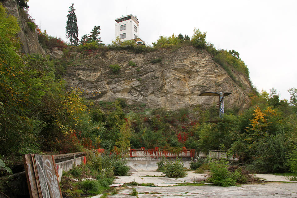 Zatímco stěny bazénu pomalu ovíjí rudé psí víno, nad okrajem lomu laškovně vykukuje věž Barrandovských teras.