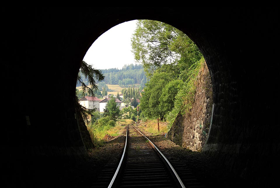 Pohled zevnitř na jižní portál Bečovského tunelu a na mechanické vjezdové návěstidlo stanice <a href=/Tema/Be%C4%8Dov%20nad%20Teplou%20%28%C5%BEst%29>Bečov nad Teplou</a>, kterému na okraji <a href=/Tema/Be%C4%8Dov%20nad%20Teplou>stejnojmenného města</a> ubíhají poslední dny jeho existence.