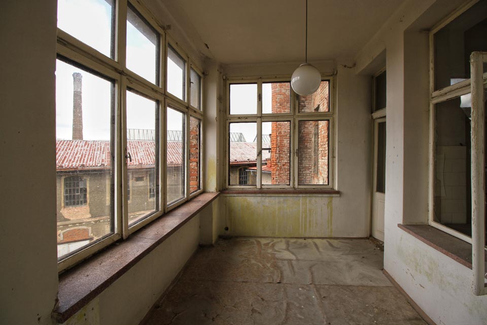 Strohá přístavba s hranatými okny a výhledem na továrnu na hraně skály. Že by pocházela ze 40. let 20. století?