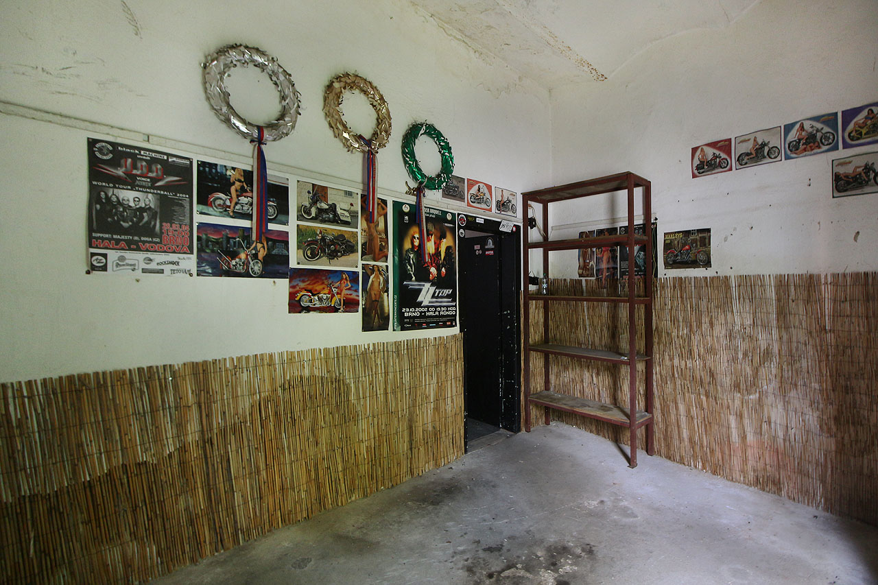 Motocyklová dílna v přízemí, ve které zůstaly pouze věnce - jako by je někdo chtěl položit na pomyslný hrob jedné z nejstarších budov dnešního Komárova, jež musela zmizet beze stopy, aby uvolnila místo více a rychleji jedoucím autům.