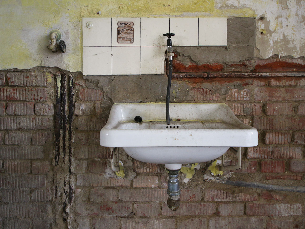 Porcelánové umyvadlo jako smutný svědek uplynulého života domu a jeho obyvatel. Plynový kohout vlevo naznačuje, že právě zde stál ohřívač vody na koupání.