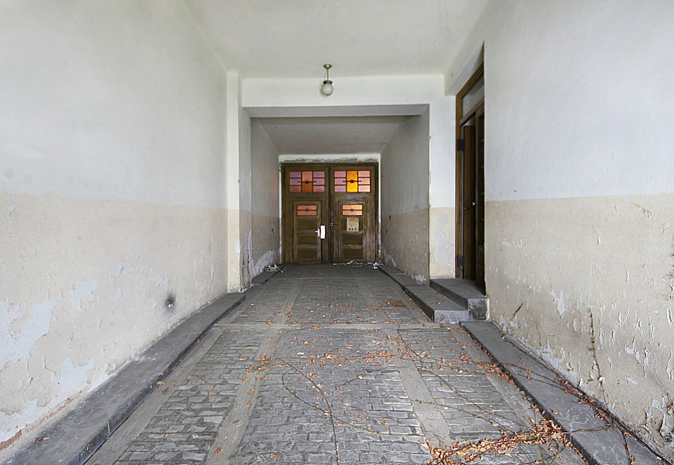 Vstup do domu skrze průjezd se špalíkovou dlažbou a mírně nepravidelná dispozice vchodu přímo vybízejí k domněnce, že bytový dům vznikl přestavbou a rozšířením užšího a přízemního venkovnského stavení.