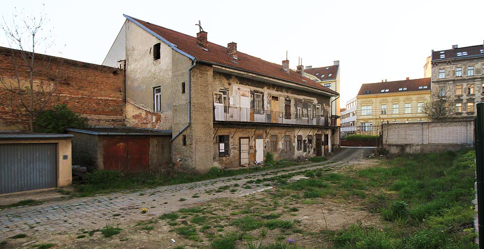 Fotografie torza původního dvora. Relativně úzký pozemek, završený směrem do ulice hlavním domem s klenutým průjezdem, lemovaly původně z obou stran dvorní vestavby - snižující se pavlačáky, kůlny na uhlí a úplně vzadu zahrádky a později garáže. Dneška se dožil poslední Mohykán.