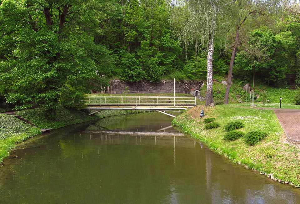 Nejzápadnější zátoka Cacovického náhona se zařezává do úbočí Holých hor, kde stojí pod opěrnou zdí také záhadná kamenná studánka. Nepřístupná zahrada zněmožňuje bližší průzkum.