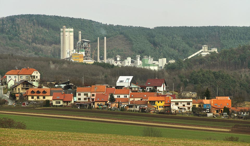 Hradba domů v Horákově a za ní hradba průmyslových objektů mokerské cementárny.