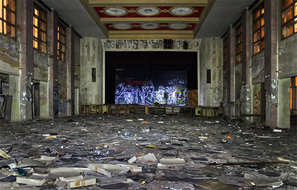 Podivná atmosféra budovy poseté deskami s nápisem na jevišti, jenž vyzývá k vraždě vlastních rodičů.