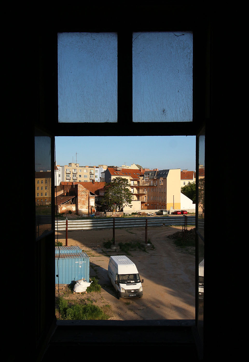 Pohled od uprázdněného dvora. tady kdysi stála pitoreskní <a href="/Tema/Oděvní továrna Kras">továrna Kras</a> se svou spoustou přístavků, hal, dvorků a komínů, jež zdědila po svých předchůdcích ve vnitrobloku. Dnešní město ale nesmí vypadat romanticky a tak továrna zmizela bez náhrady.