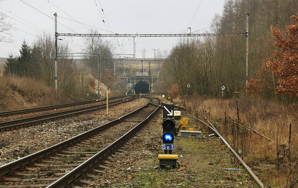 Severní portál Havlíčkobrodského tunelu. Vlevo dvě koleje <a href="/Tema/Železniční trať Brno – Havlíčkův Brod">trati z Brna</a> a jedna kolej <a href="/Tema/Železniční trať Havlíčkův Brod – Pardubice">dráhy z Pardubic</a>, vpravo kolej <a href="/Tema/Vlečka Havlíčkův Brod - správa silnic">zrušené vlečky do areálu obalovny stavební firmy</a>.
