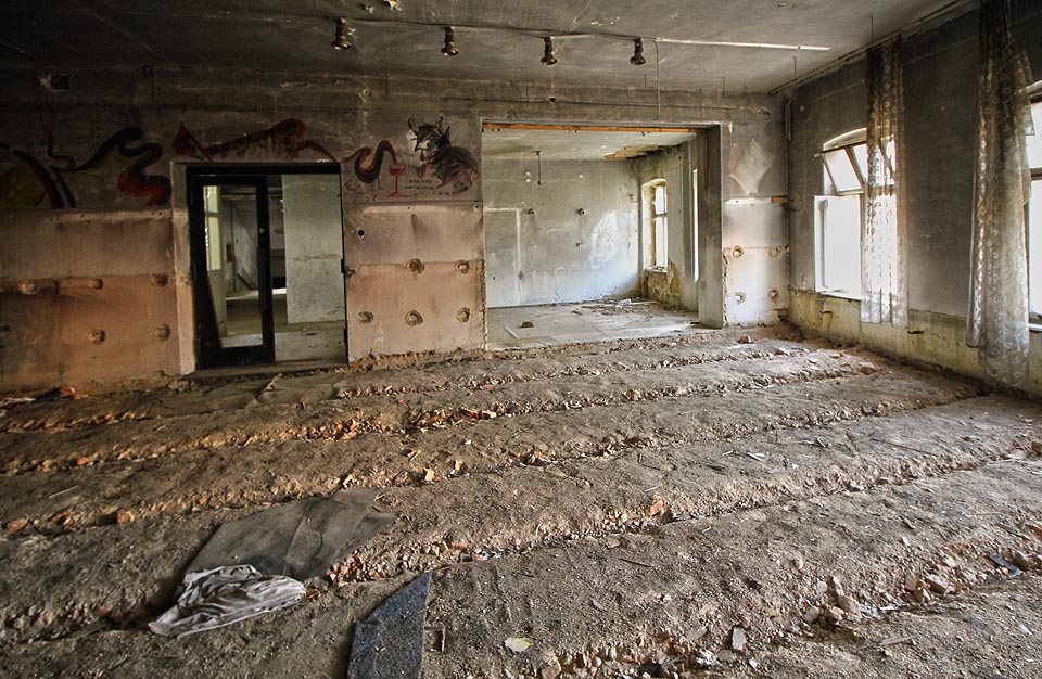 Hotelová restaurace už pár let zeje prázdnotou. Ze zplihlých záclon a pokreslených stěn jako by ale pořád tiše zaznívala ozvěna hudby, cinkot sklenic a příborů…