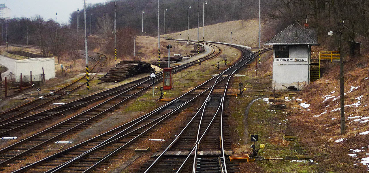 Stavědlo, telefonní budka a vlečka do cukrovaru. Vpravo je vidět odbočující kolej tratě do <a href=/Tema/Hevl%C3%ADn%20%28%C5%BEst%29>Hevlína</a>.