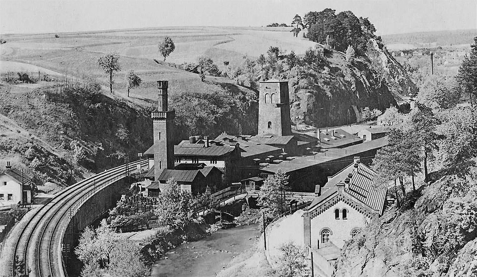 Pohled neznámého autora na huť Klamovku od jihu. Na levém břehu řeky (tj. vpravo) je dobře patrná provozní budova, která byla v 70. letech 20. století zbourána v souvislosti s výstavbou silnice z <a href="/Tema/Lipůvka">Lipůvky</a> do <a href="/tema/Blansko">Blanska</a>. Ani na tomto pohledu, stejně jako na žádném jiném, nelze jasně rozhodnout o (ne)existenci úzkokolejky vedoucí k <a href="/Tema/Blansko (žst)">nádraží</a>.