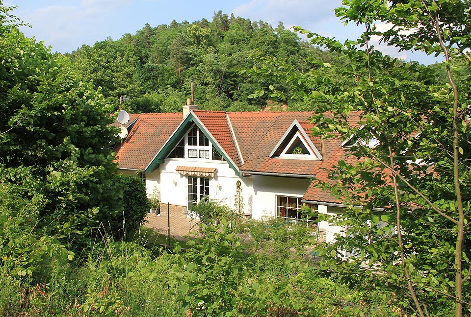 Pohled na budovu nádraží ze strany od kolejí <a href=/Tema/Star%C3%A1%20Ti%C5%A1novka>zrušené dráhy</a>. I po přestavbách lze rozeznat hlavní štít a kamennou podezdívku původní zastávky.