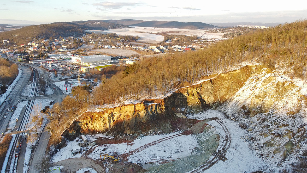 Letecký pohled na bývalý kamenolom, ve kterém se v roce 2021 rozběhly stavební práce na výstavbě bytového komplexu Diorit. Lom bude netradičně a zajímavě vyplněn zástavbou, tunel však zřejmě v jeho úbočí zůstane.